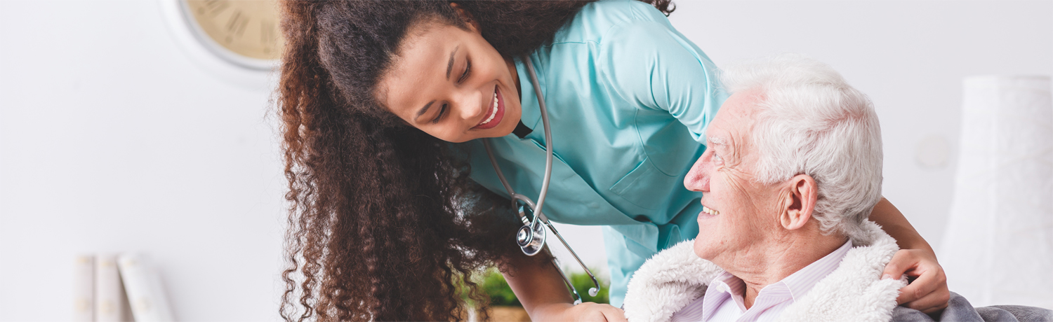 Panorama of a happy nurse with a stethoscope covering an elderly man with a blanket Panorama of a happy nurse with a stethoscope covering an elderly man with a blanket
